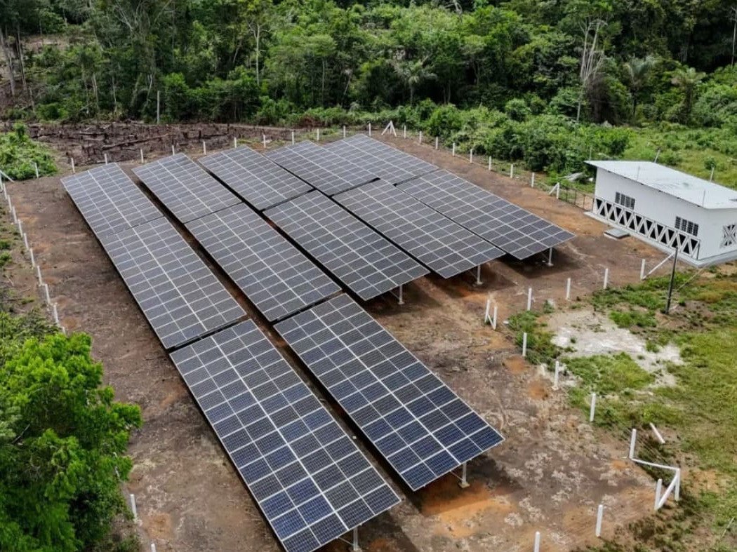 Usina solar de solo ao lado de edifica&ccedil;&atilde;o, em &aacute;rea de floresta